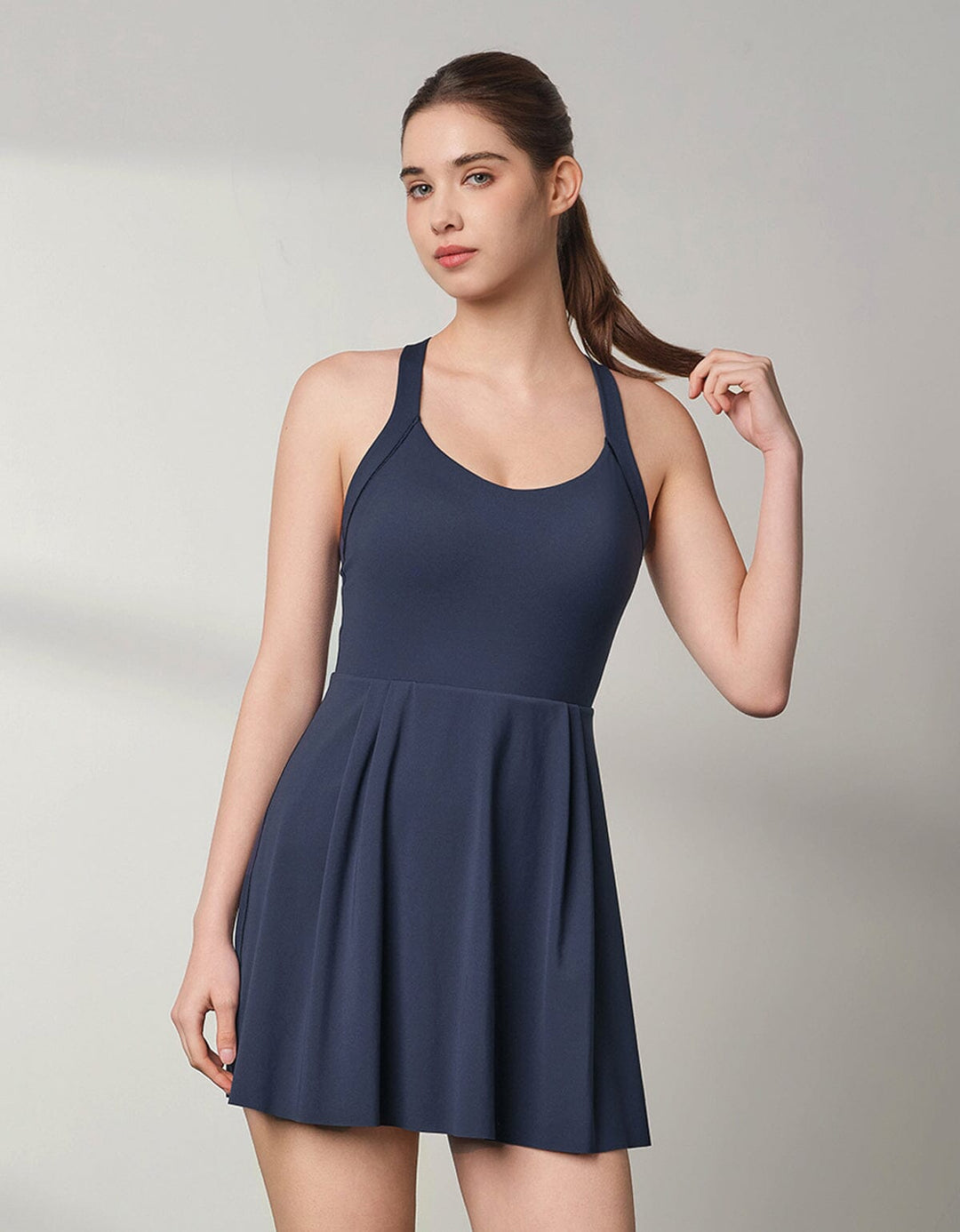 A beautiful girl is wearing a navy blue FLOAT Tennis Dress from Her own words SPORTS 